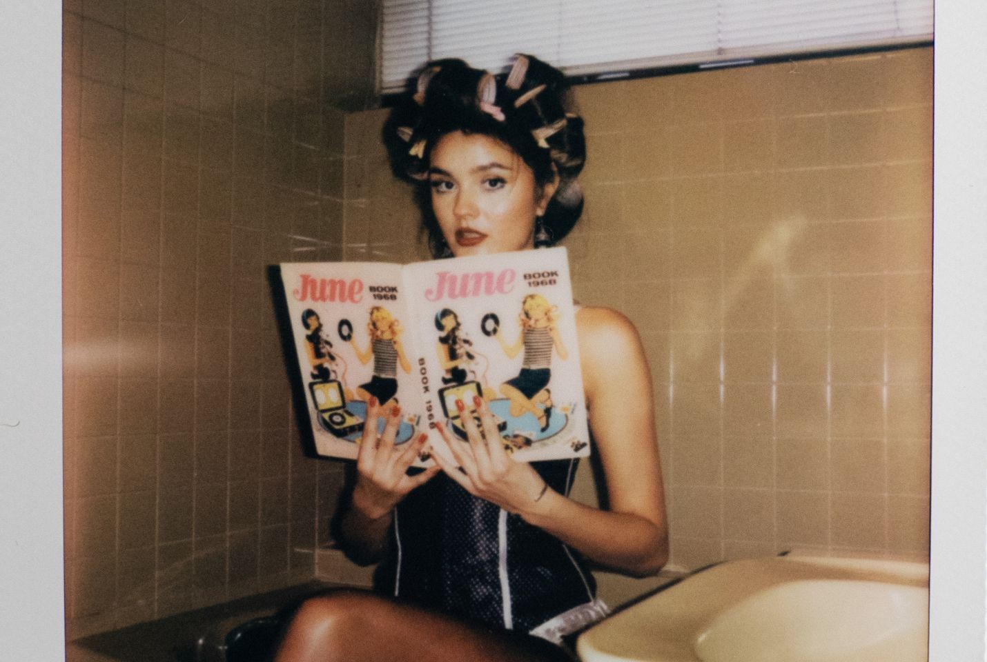 Ruby Roberts holding a magazine with rollers in her hair